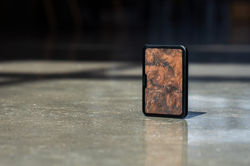 An Ohsnap Wallet 2 clad in burlwood standing upright, its grain lit from the side.