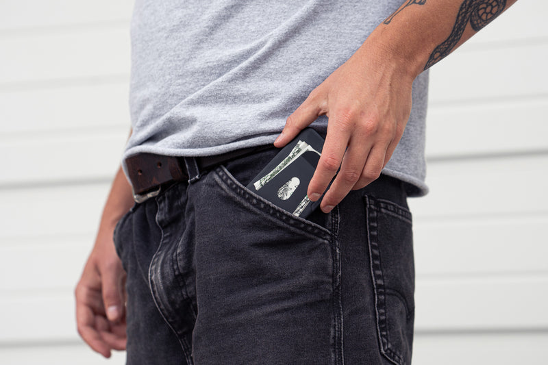 The wallet drawn from a jeans pocket with banknotes held under its clip cover.