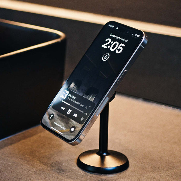 Smartphone on a black stand displaying the time and music player interface.
