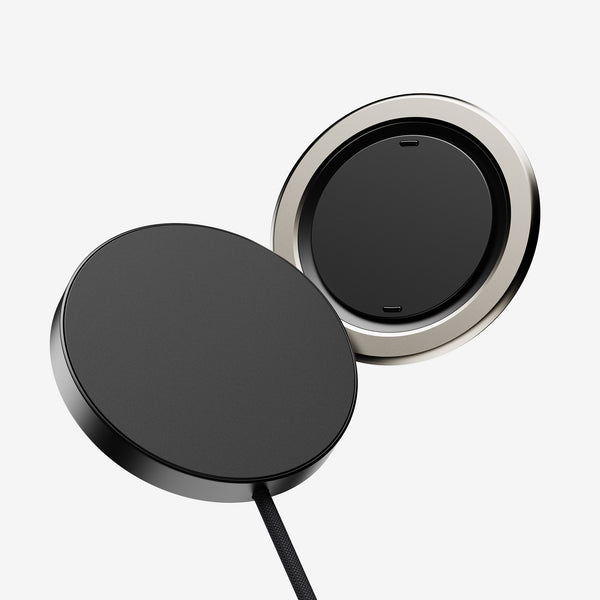 Wireless charging pad with a sleek black surface and a metallic circular edge, connected by a cable.