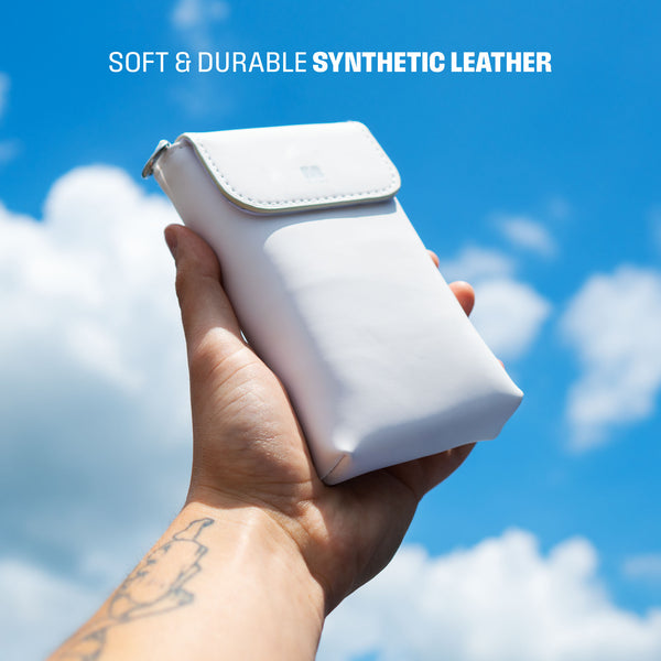 A hand holds a white travel sleeve made of synthetic leather against a blue sky with clouds.