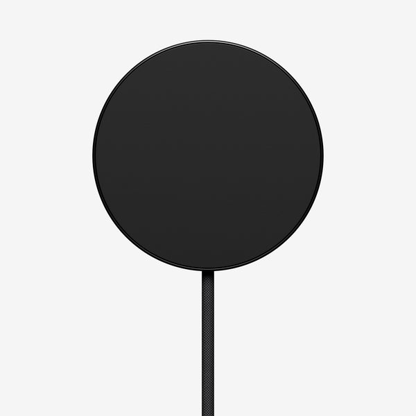 Round black wireless charger with a connected cable.