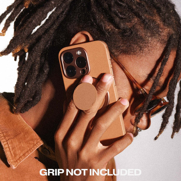 Person holding a brown phone case with a circular grip, wearing sunglasses and a brown shirt.