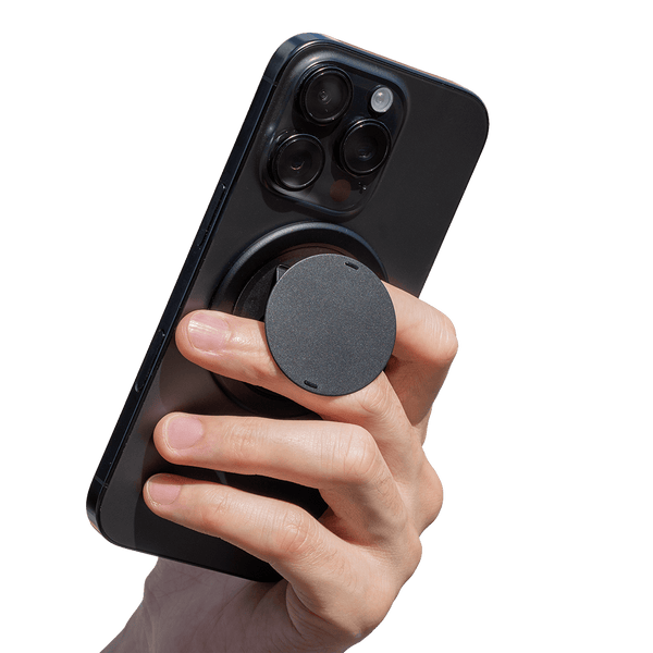 Hand holding a smartphone with a circular grip attached to the back for better handling.