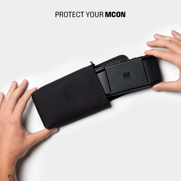 Black travel sleeve holding an MCON device, with hands positioned around it.