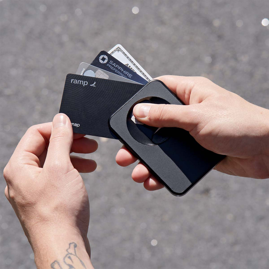 A hand holds a black wallet with several cards partially visible, set against a textured surface.