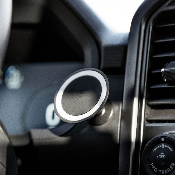 Magnetic car mount attached to a dashboard, designed for holding devices securely.