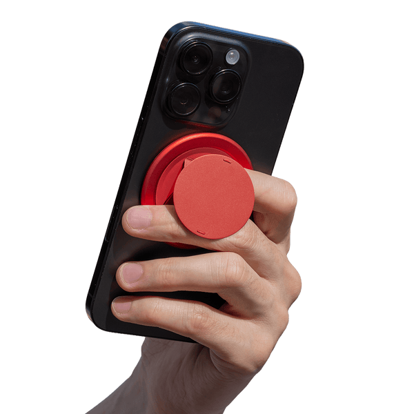 Hand holding a smartphone with a red circular grip attached to the back.