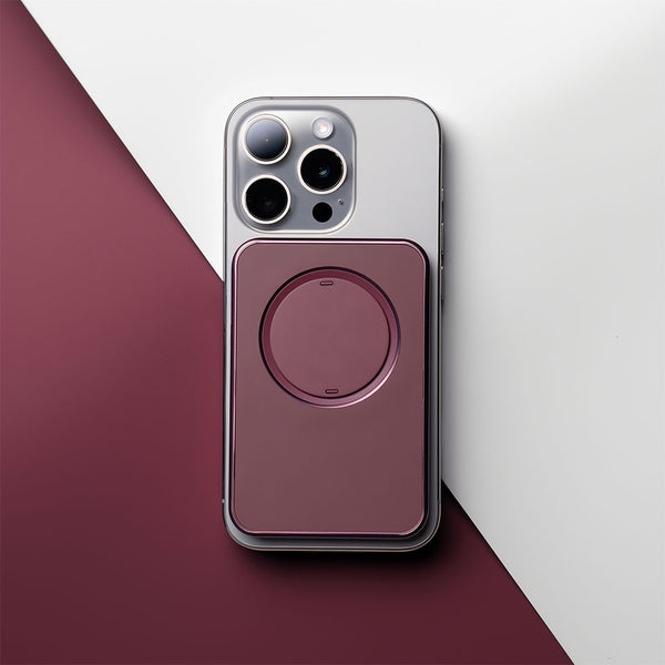 Magenta snap grip wallet attached to the back of a smartphone on a two-tone background.