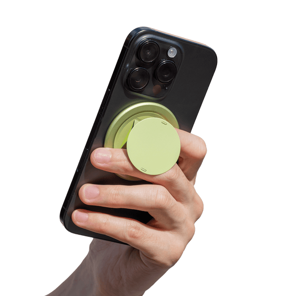 Hand holding a smartphone with a circular green grip attached to the back.