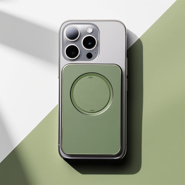 A smartphone with a green snap grip wallet attached to its back, placed on a two-tone surface.