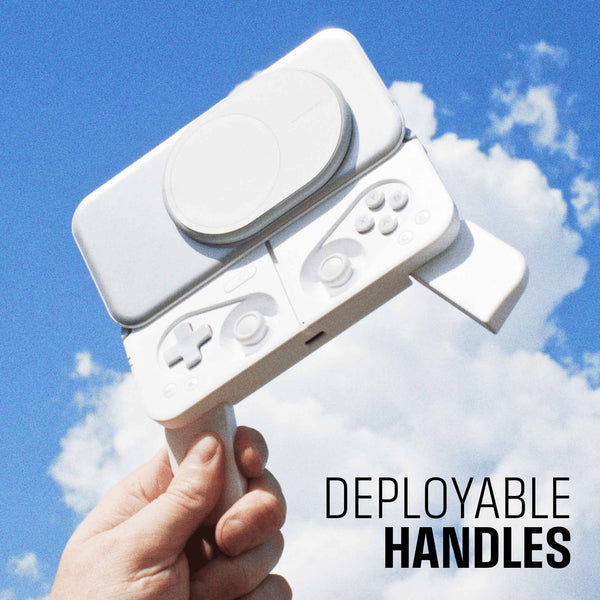 A hand holds a white gaming controller with deployable handles against a blue sky with clouds.