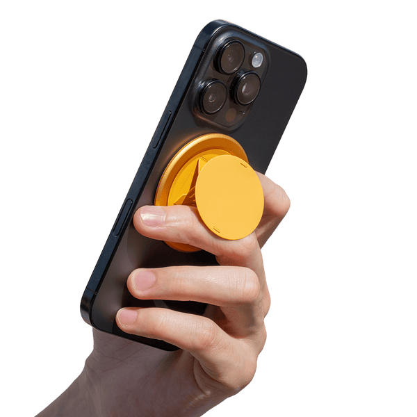 Hand holding a smartphone with a yellow circular grip attached to the back.