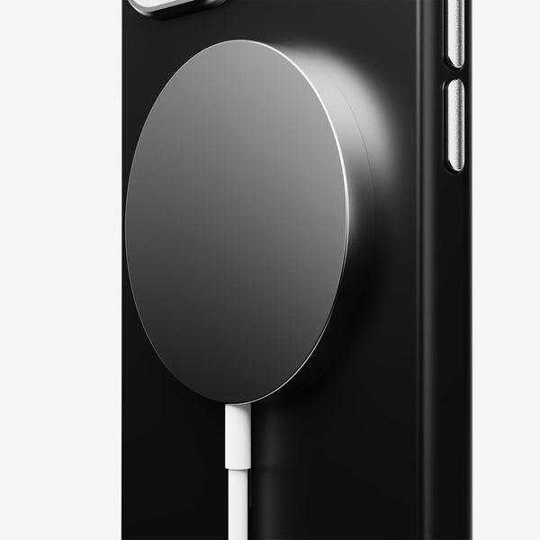 Magnetic charging pad attached to a black phone case with a white charging cable connected.