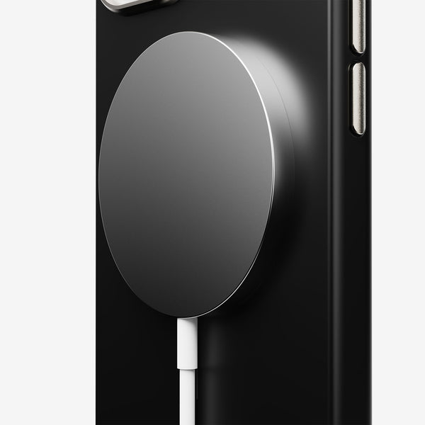 Magnetic charging pad attached to a black phone case with a white charging cable connected.