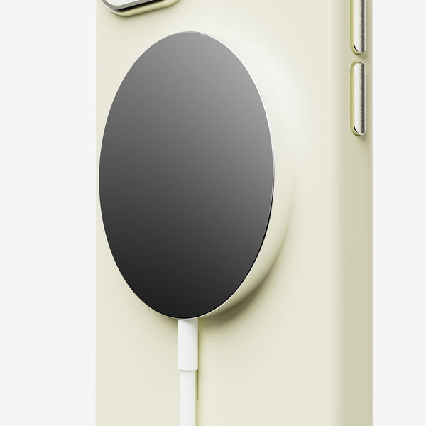 Close-up of a light yellow phone case featuring a circular magnetic charging pad and a white charging cable.