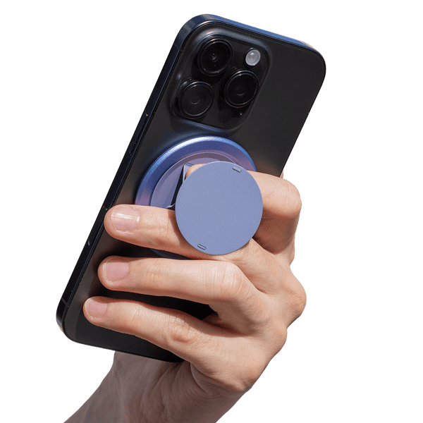 A hand holding a smartphone with a circular grip attached to the back for better handling.