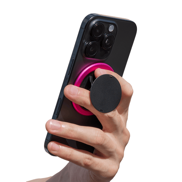 Hand holding a smartphone with a circular grip attached to the back, featuring a pink ring and a black finger holder.