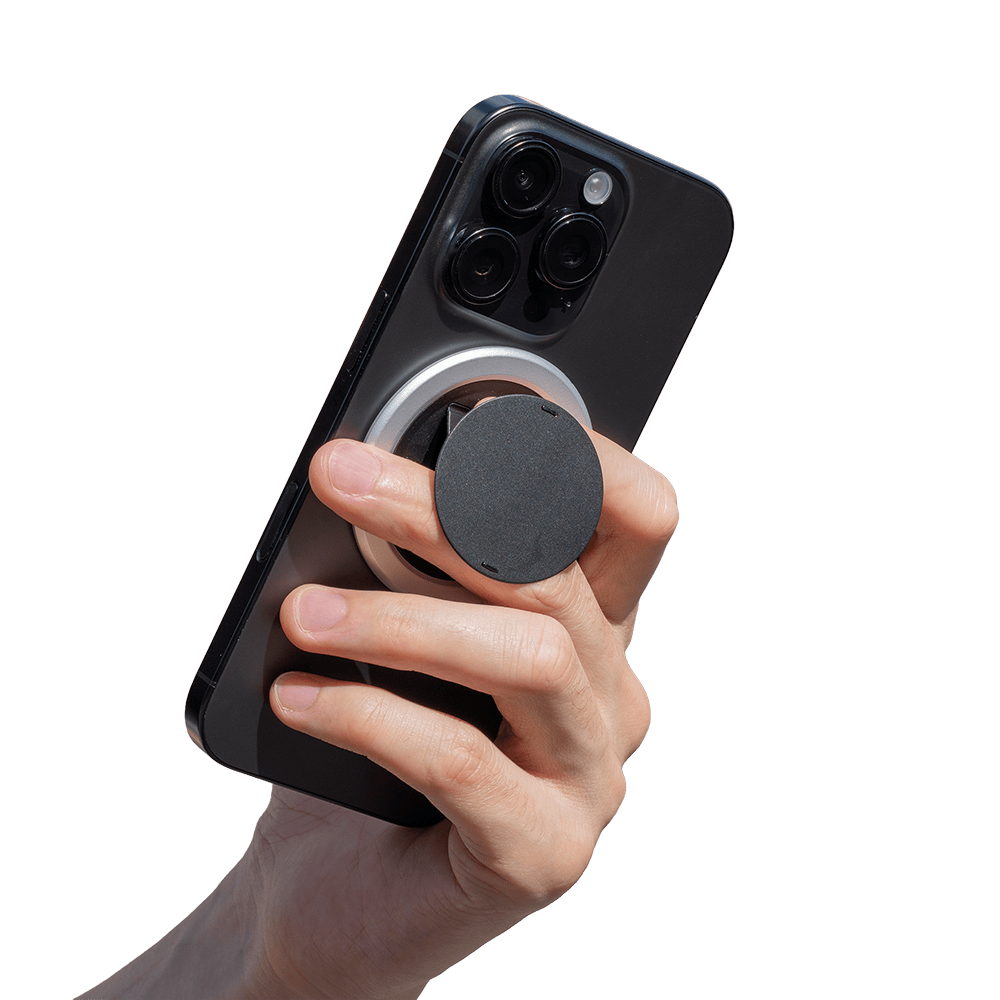 A hand holding a smartphone with a circular grip attached to the back.
