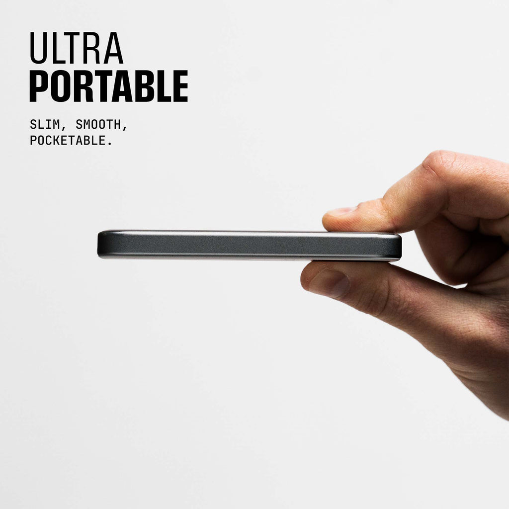 A hand holds a slim, portable device against a plain background.