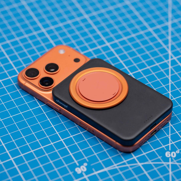 Orange smartphone with a black and orange accessory attached, placed on a blue grid background.