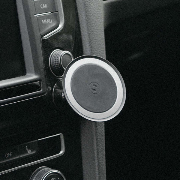 Car mount attached to a dashboard, featuring a circular design with a smooth surface and a logo in the center.